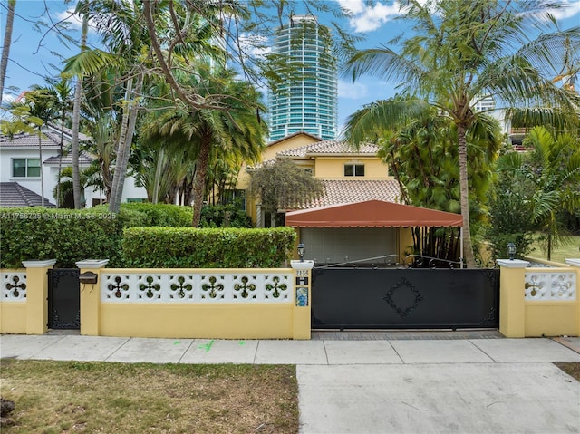 view of front of property with a fenced front yard, a gate, a tiled roof, and stucco siding