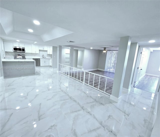 interior space featuring marble finish floor, baseboards, a sink, and recessed lighting