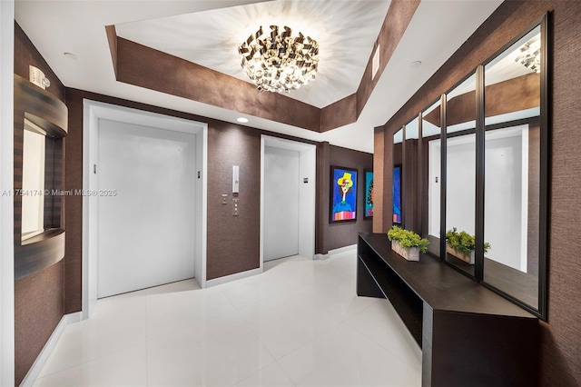 hallway featuring elevator, tile patterned flooring, and a raised ceiling