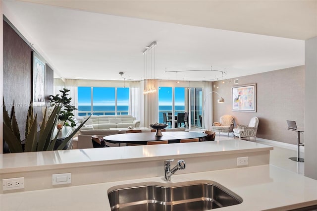 kitchen featuring track lighting, light countertops, open floor plan, and a sink