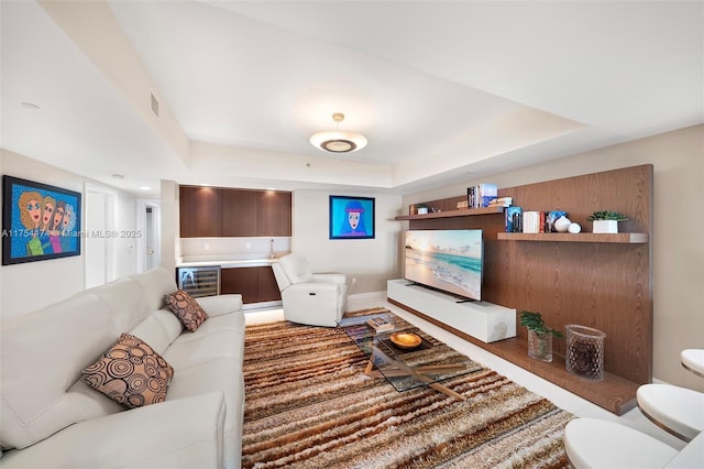 living area with beverage cooler, visible vents, and a tray ceiling