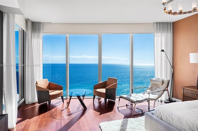 bedroom featuring a water view, a notable chandelier, and wood finished floors