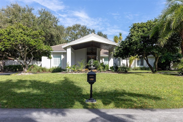 view of front of house featuring stucco siding, fence, and a front yard