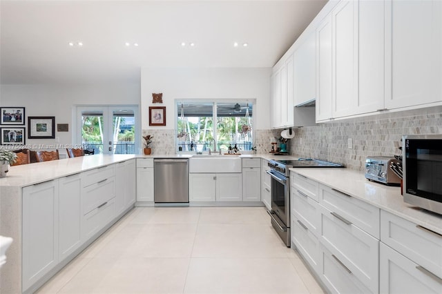 kitchen with plenty of natural light, a sink, stainless steel appliances, backsplash, and light tile patterned flooring