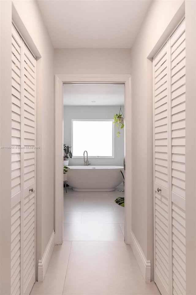 corridor featuring tile patterned floors and baseboards