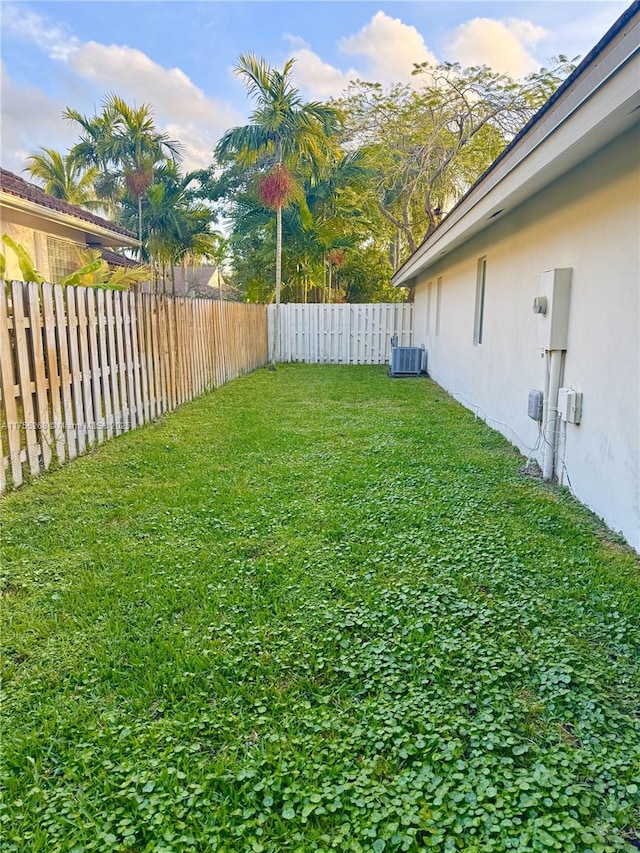 view of yard with a fenced backyard and central AC unit