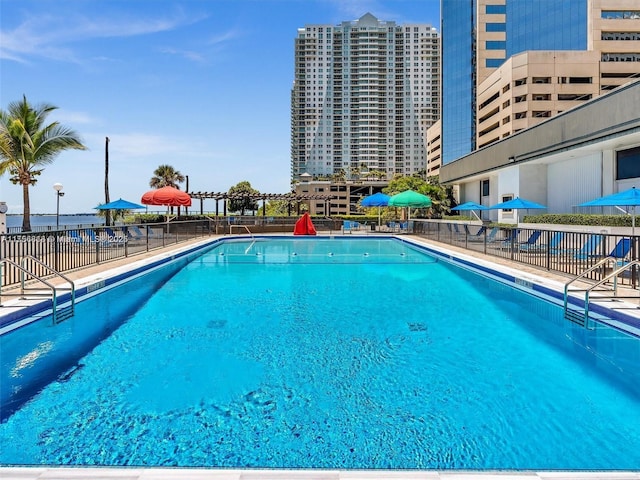 community pool with a city view and fence