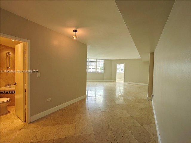 hall with light tile patterned flooring, a sink, and baseboards