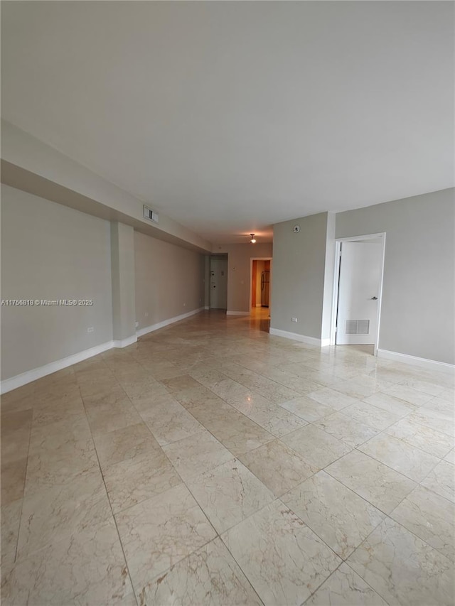 unfurnished living room with marble finish floor, visible vents, and baseboards