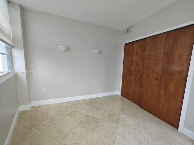 unfurnished bedroom featuring a closet, visible vents, and baseboards