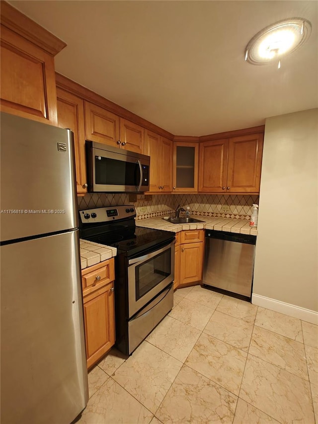 kitchen featuring brown cabinetry, tasteful backsplash, tile counters, and stainless steel appliances