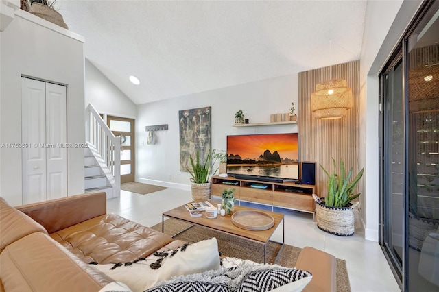 living area featuring stairs, high vaulted ceiling, and baseboards