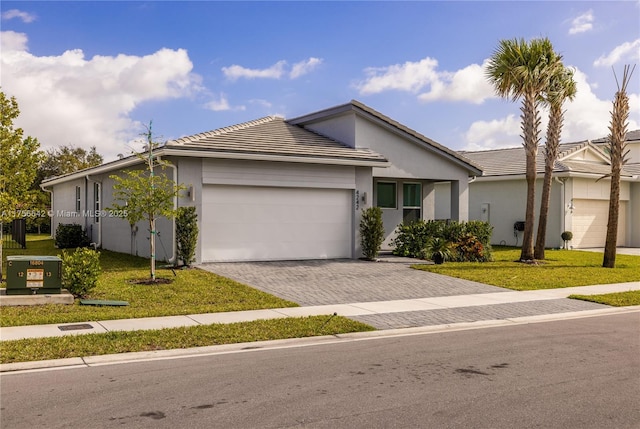 single story home with an attached garage, a front lawn, decorative driveway, and stucco siding