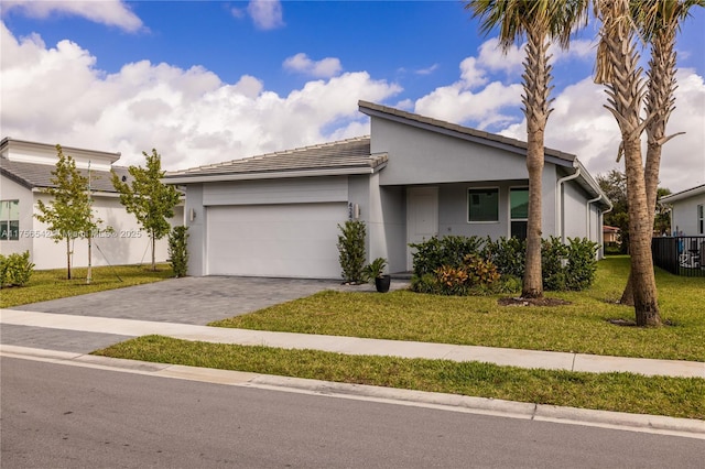 view of front of home with a garage, fence, decorative driveway, a front lawn, and stucco siding