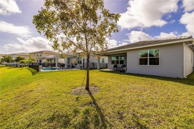 rear view of house with a fenced in pool, a patio, a yard, stucco siding, and fence