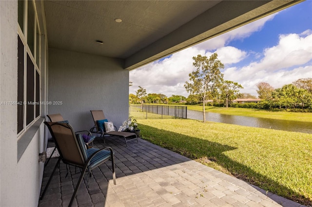 view of patio with a water view and fence