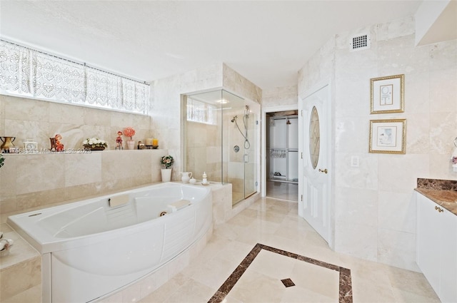 bathroom with tile walls, visible vents, a stall shower, vanity, and a tub with jets