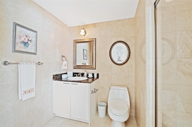 full bath with toilet, vanity, tile walls, a tile shower, and tile patterned floors