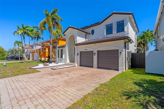 mediterranean / spanish-style house featuring a tiled roof, a front lawn, and fence