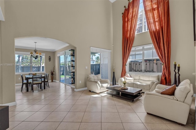 living room with baseboards, a high ceiling, an inviting chandelier, light tile patterned flooring, and arched walkways