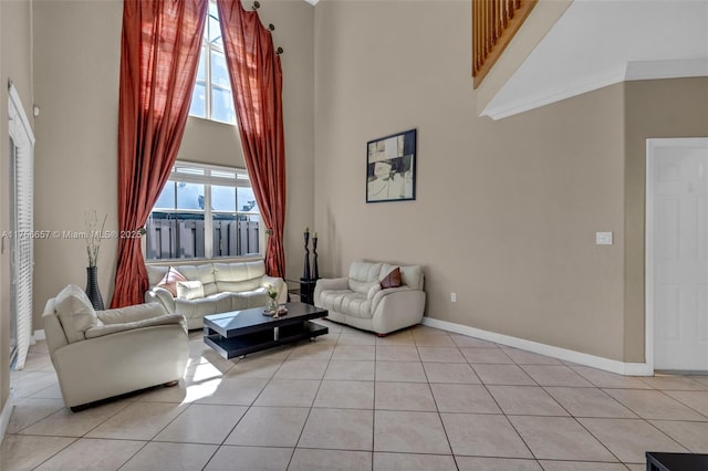 living area featuring light tile patterned flooring, baseboards, and a towering ceiling