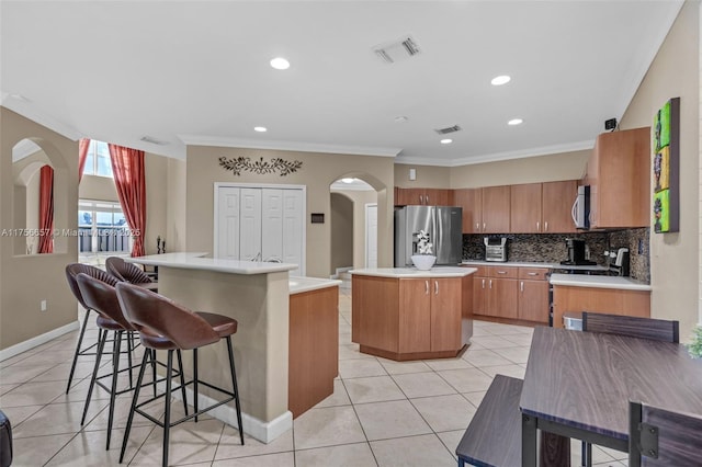 15509 SW 139th Ct, Miami, FL 33177 - kitchen with stainless steel appliances, a kitchen island, arched walkways, ornamental molding, and light tile patterned flooring