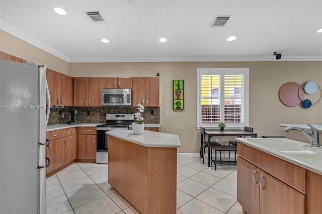 kitchen with a sink, stainless steel appliances, a kitchen island, and ornamental molding