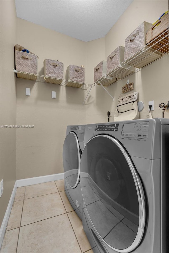 laundry room with light tile patterned floors, baseboards, laundry area, separate washer and dryer, and a textured ceiling