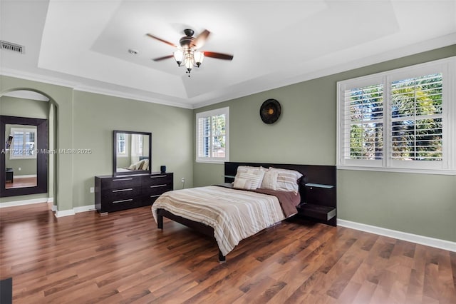 bedroom with visible vents, a raised ceiling, arched walkways, and wood finished floors