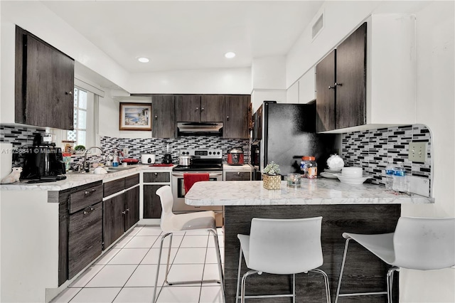 kitchen with dark brown cabinets, a peninsula, freestanding refrigerator, electric stove, and a sink