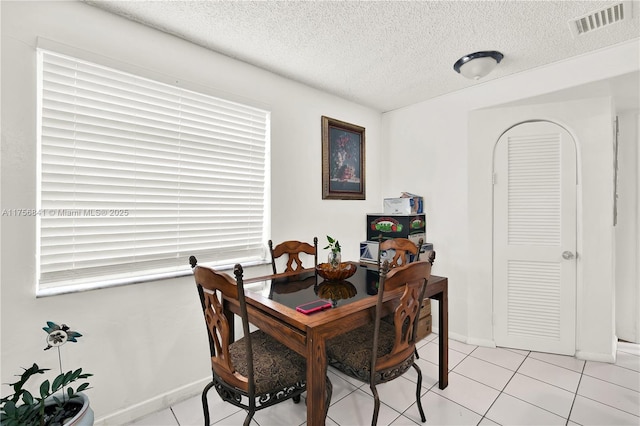 dining area with light tile patterned floors, visible vents, baseboards, and a textured ceiling