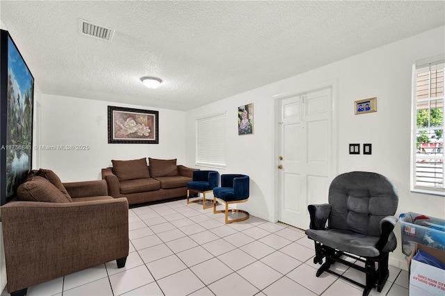 living area featuring light tile patterned floors, visible vents, and a textured ceiling