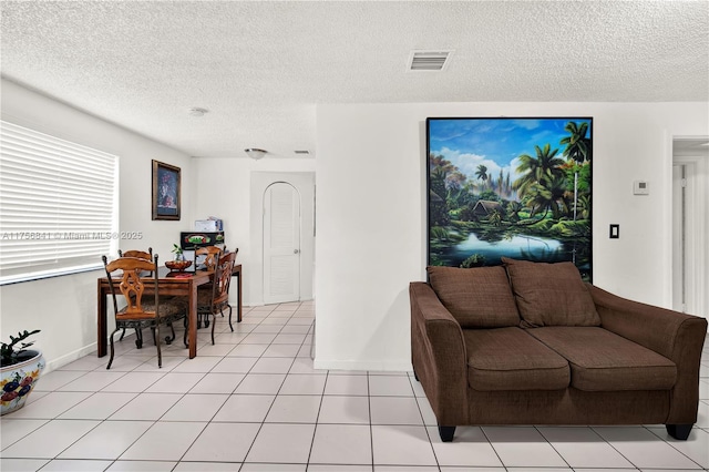 living area with light tile patterned floors, visible vents, baseboards, and a textured ceiling