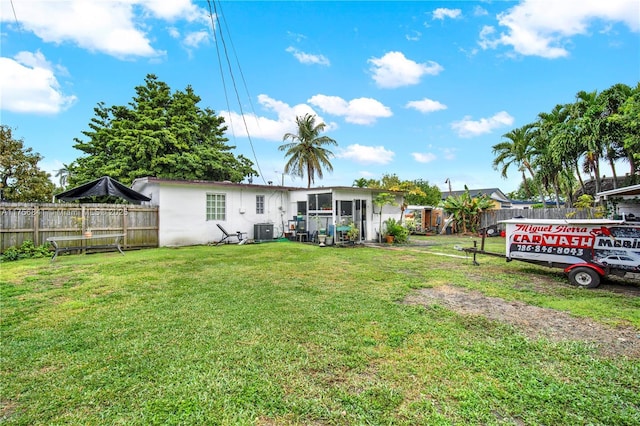 back of property featuring central air condition unit, a yard, and fence