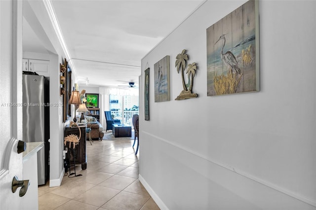 hall featuring light tile patterned floors and baseboards