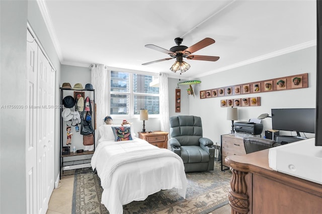 bedroom featuring ornamental molding, a closet, light tile patterned flooring, and a ceiling fan