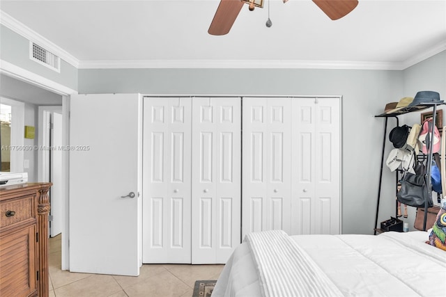 bedroom with light tile patterned floors, visible vents, a ceiling fan, ornamental molding, and a closet