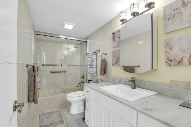 bathroom with tiled shower, vanity, and toilet