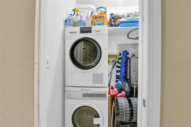 clothes washing area featuring stacked washing maching and dryer