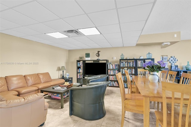 living area featuring a drop ceiling and light tile patterned flooring