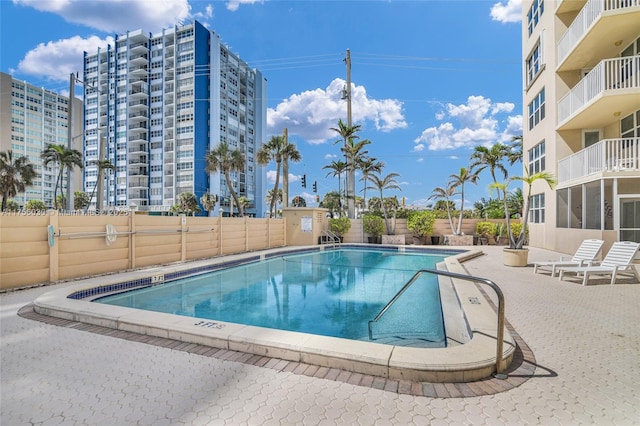 community pool with a patio area and fence