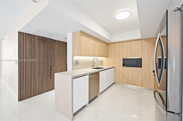 kitchen featuring modern cabinets, marble finish floor, stainless steel appliances, light brown cabinets, and a sink