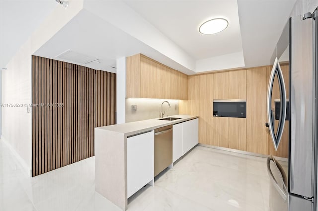 kitchen with modern cabinets, appliances with stainless steel finishes, marble finish floor, a sink, and light brown cabinetry