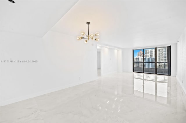 unfurnished room featuring a chandelier, expansive windows, marble finish floor, and baseboards