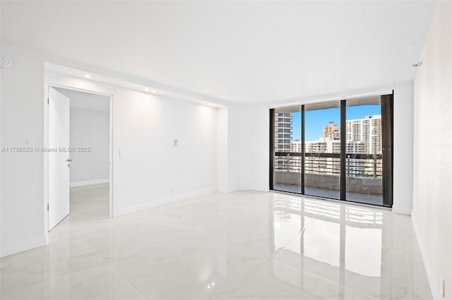 unfurnished room featuring expansive windows and baseboards