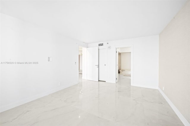 unfurnished room with marble finish floor, baseboards, and visible vents
