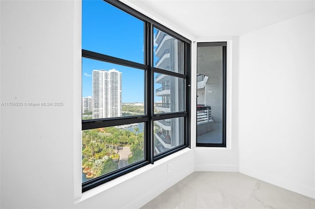 spare room featuring baseboards, marble finish floor, and a city view