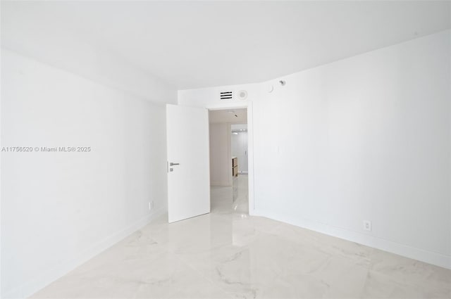 empty room featuring marble finish floor and baseboards