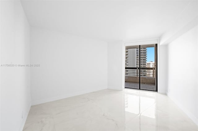 spare room with marble finish floor, baseboards, and a wall of windows
