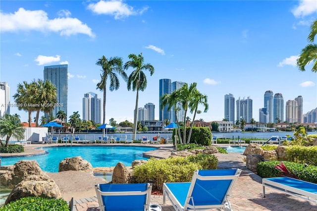 community pool with a patio area, fence, and a city view